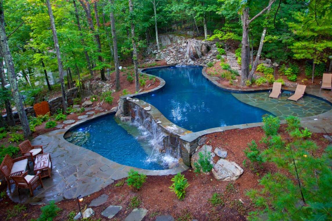 A gunite pool in the woods with a waterfall