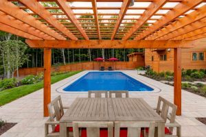 Auburn brown pergola with seating on the side of a beautiful blue pool