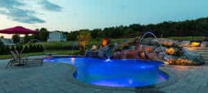 rock outcroppings on the side of lit-up swimming pool