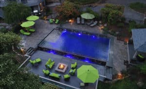 Aerial view of pool with green seating sun umbrellas, and fireplace