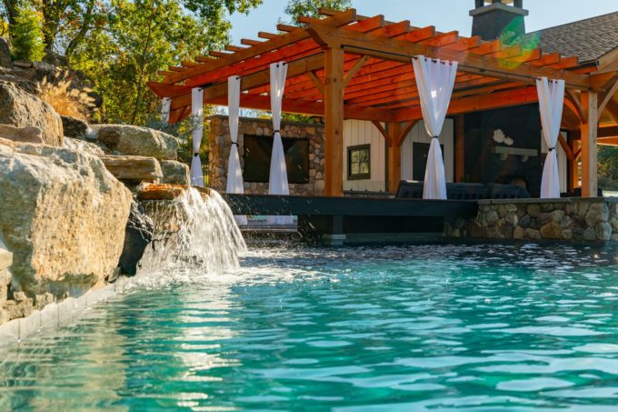 Burnt orange pergola next to pool with waterfall