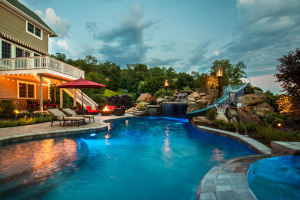 Enchanting backyard pool at night, enhanced by mesmerizing fire features, creating a warm and inviting ambiance.