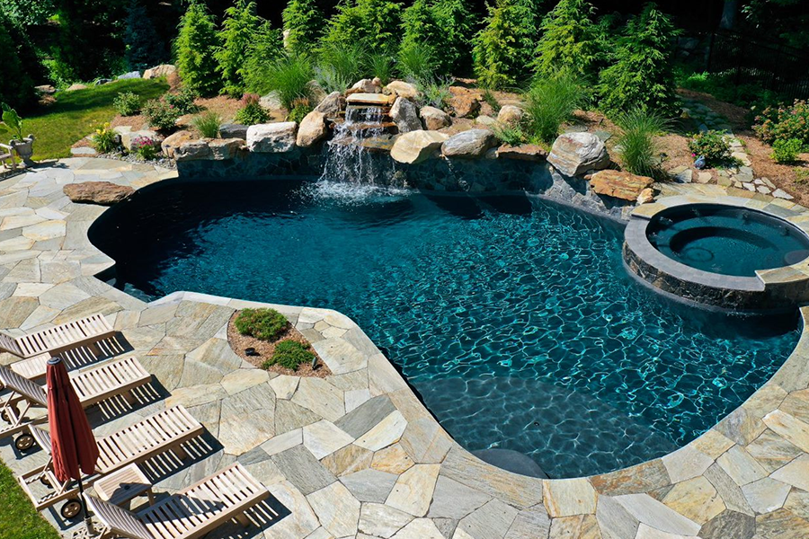Outdoor pool surrounded by nature with stone and water features