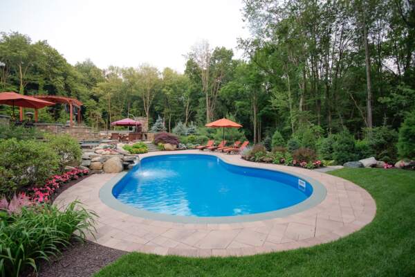 Scenic outdoor pool nestled amidst beautiful landscaping, blending natural elements for a tranquil and picturesque setting.