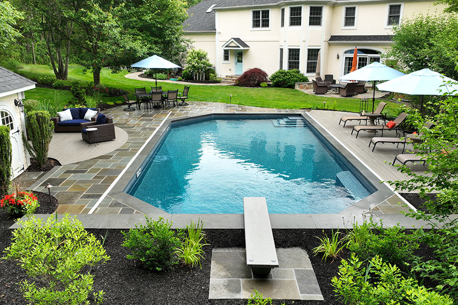 Elegant minimalist pool with clean, clear water, surrounded by stylish pool umbrellas and a sofa set, maintained by NY, NJ, CT pool servicing professionals.