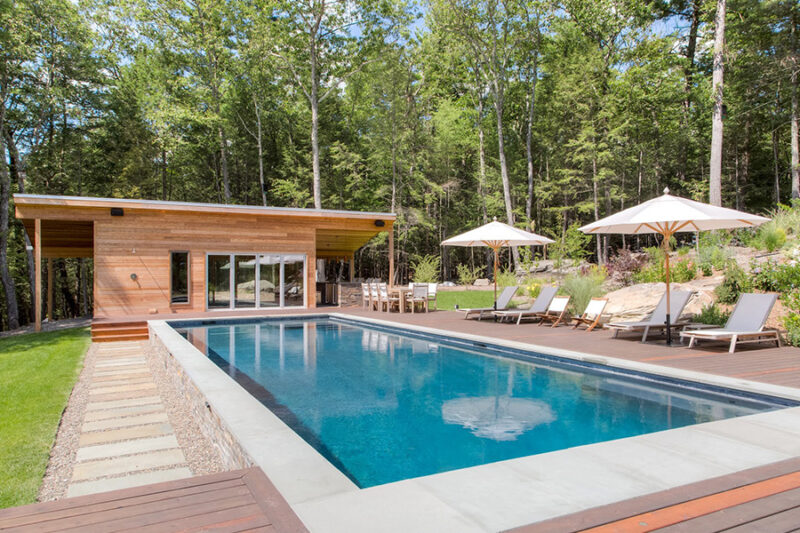 Modern backyard with a sleek pool installed by fiberglass pool installers, surrounded by lush greenery and decking