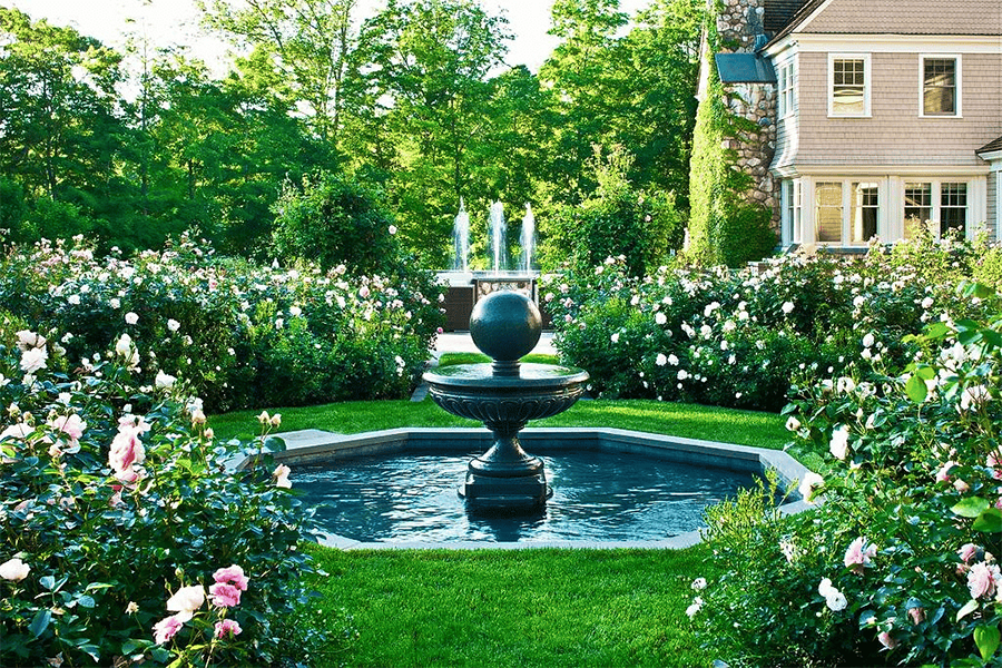 Beautiful fountain surrounded by blooming flowers and greenery showcasing landscaping tips for noise reduction in a tranquil yard