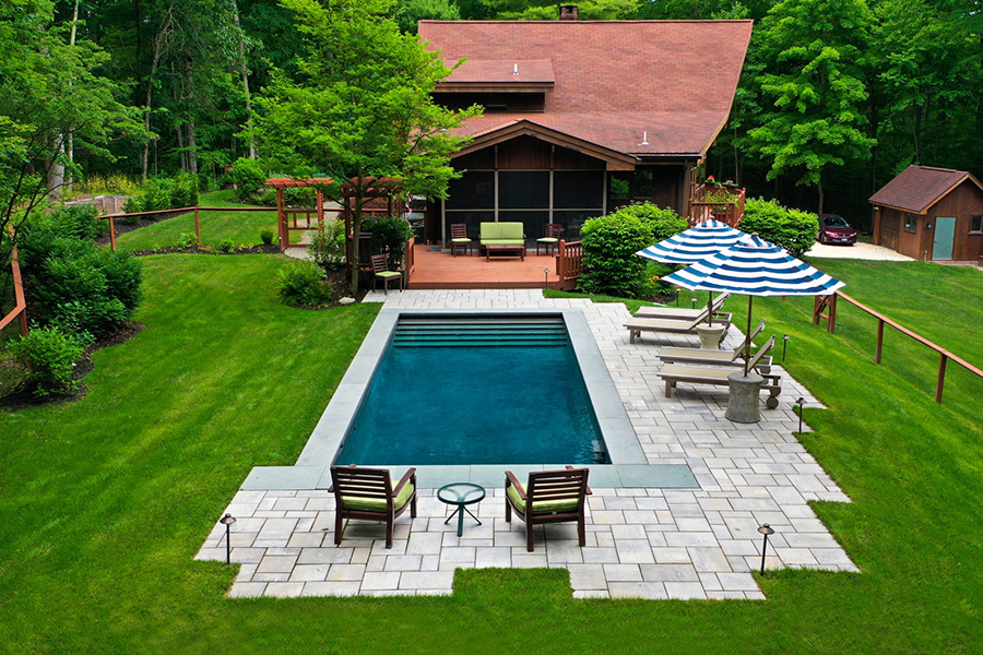 Modern rectangular pool with lush greenery, layered plants, and a serene outdoor setting showcasing rectangular pool landscaping ideas