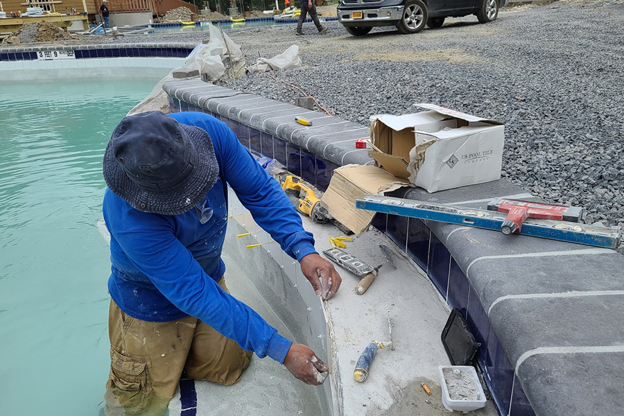 Worker performing gunite pool maintenance, showcasing tools and materials, illustrating one of the types of pool renovations